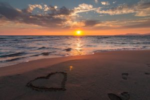 coeur dessiné sur une plage avec un coucher de soleil