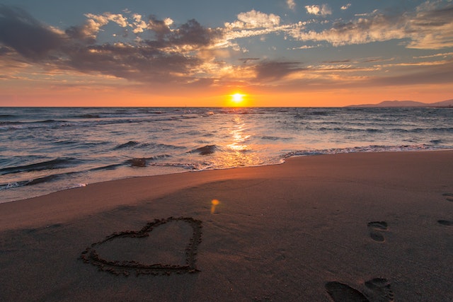 coeur dessiné sur une plage avec un coucher de soleil