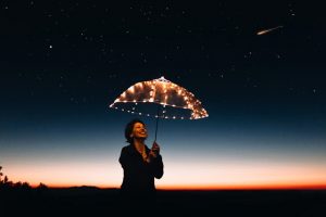 femme heureuse tenant un parapluie lumineux a la nuit tombée