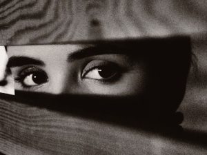 femme regardant a travers des barreaux en bois